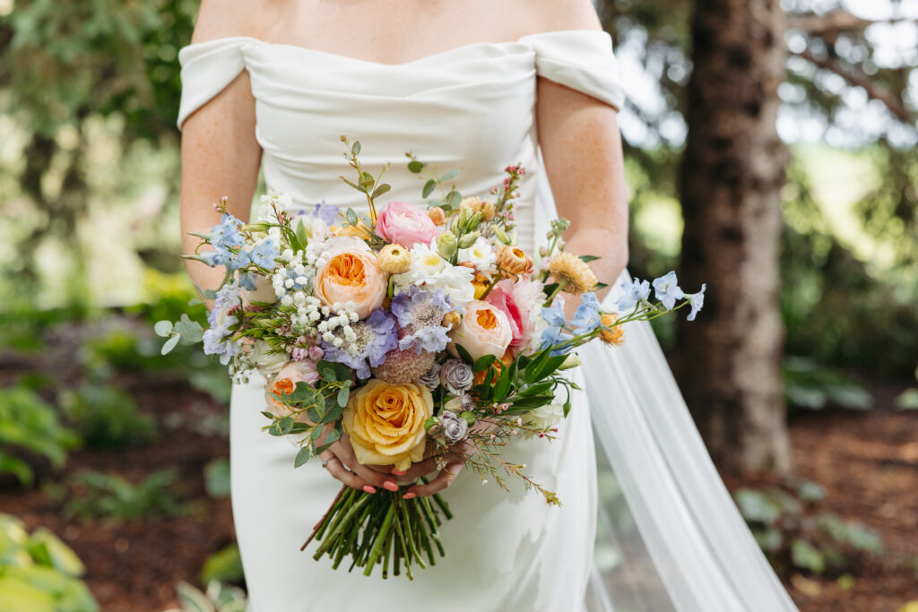 a detail shot of a bride holding a very vibrant bouquet of summer flowers