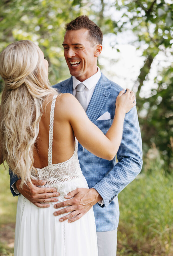 bride and grooms share an embrace with big smiles after just sharing their first look outside during summer in Minnesota